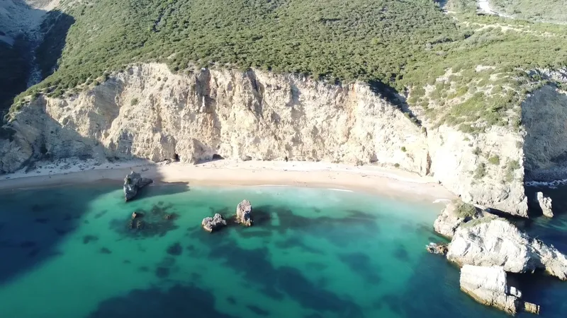 Drone view of pale sea cliffs above a turquoise bay.