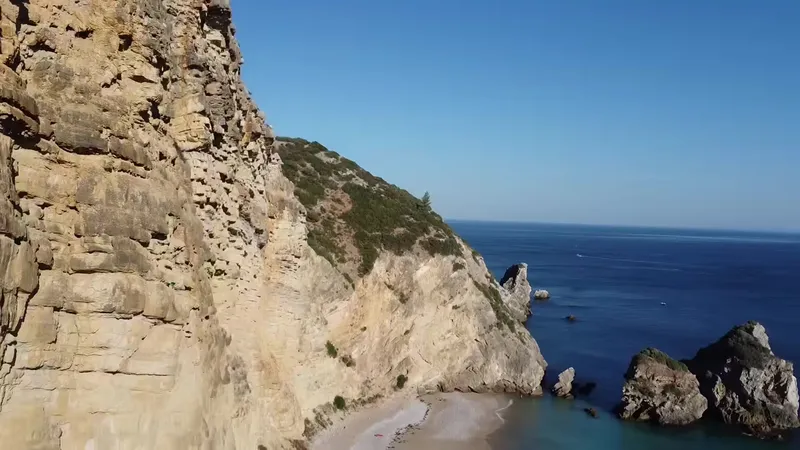 Drone view of tall sea cliffs above a small beach.
